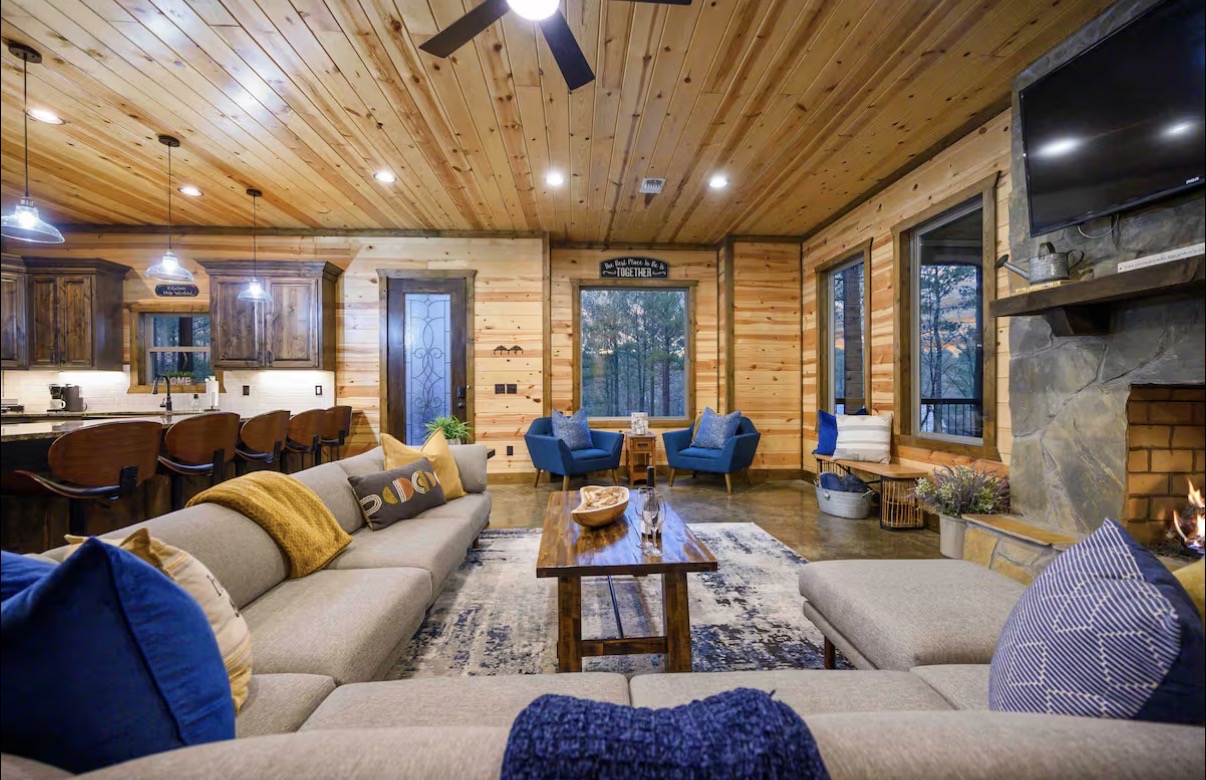 Sound of Sunshine — great room from behind the sectional with fireplace and mounted TV