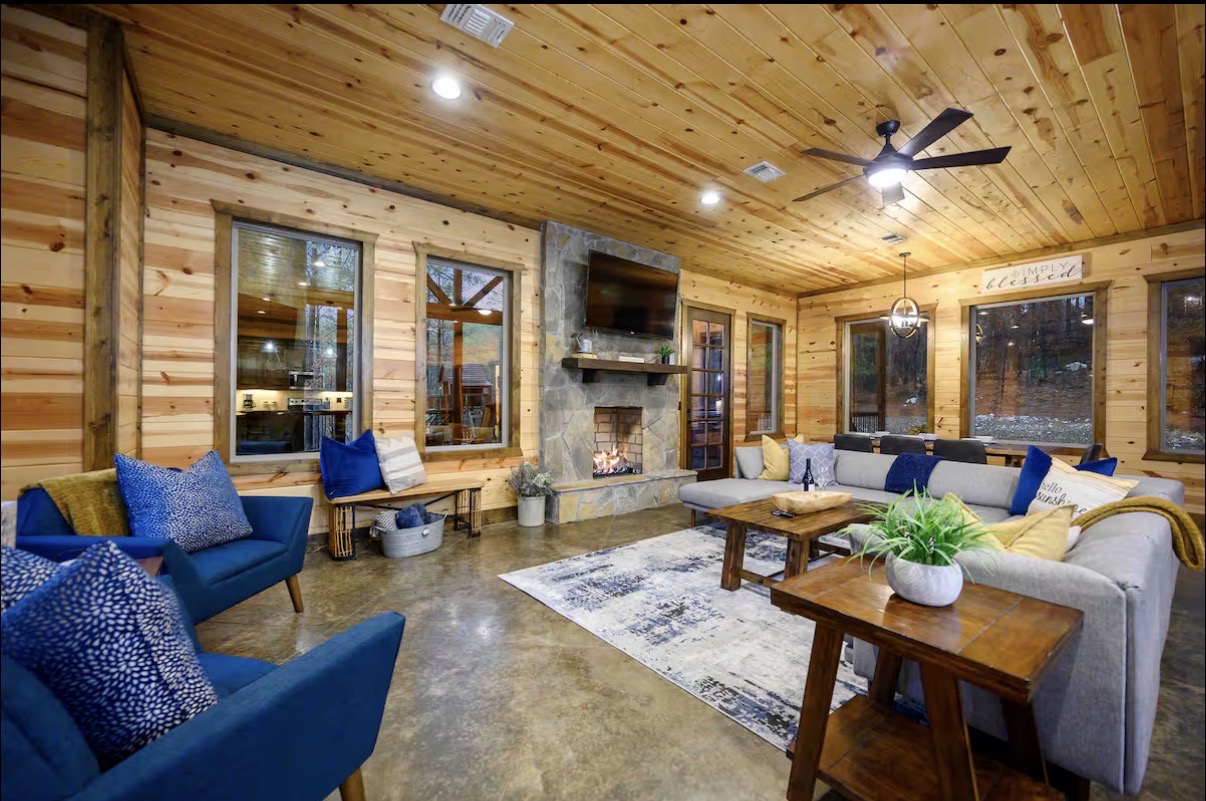 Sound of Sunshine — living room with lit stone fireplace, blue accent chairs and dining beyond