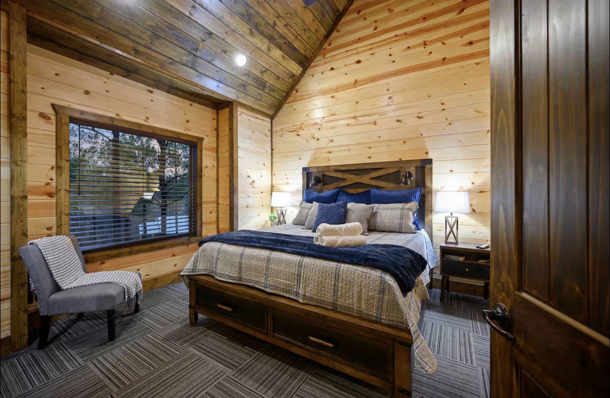 Sound of Sunshine — king bedroom with vaulted ceiling, reading chair and forest window