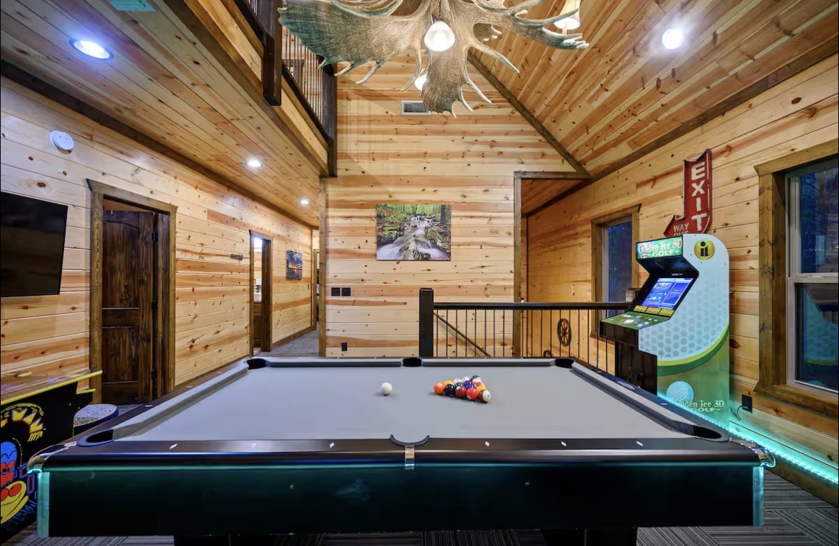 Sound of Sunshine — game room pool table under antler chandelier with loft above