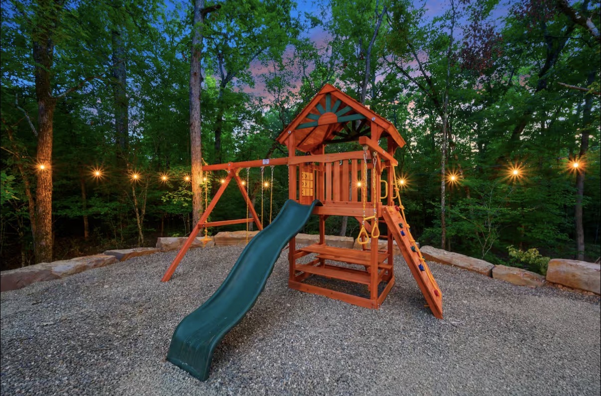 As Good As It Gets — cedar playset with swings and slide under string lights