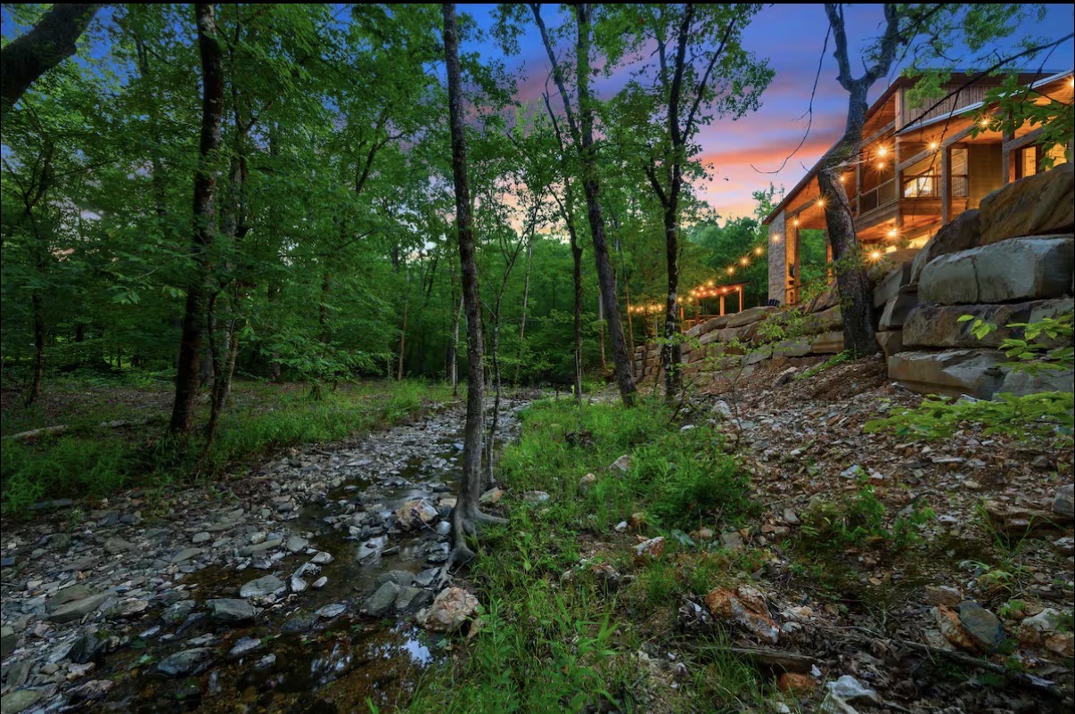 As Good As It Gets — creekside cabin lit up at sunset