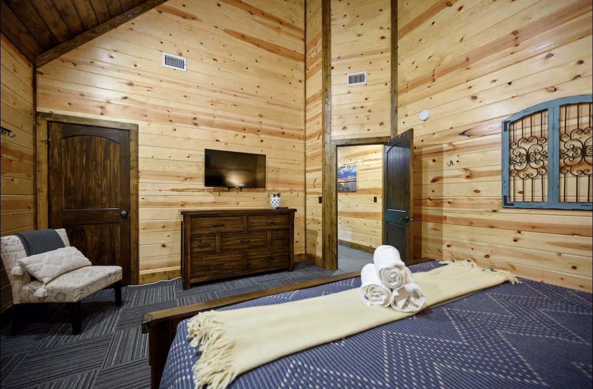Sound of Sunshine — king bedroom with dresser, mounted TV and en-suite doorway