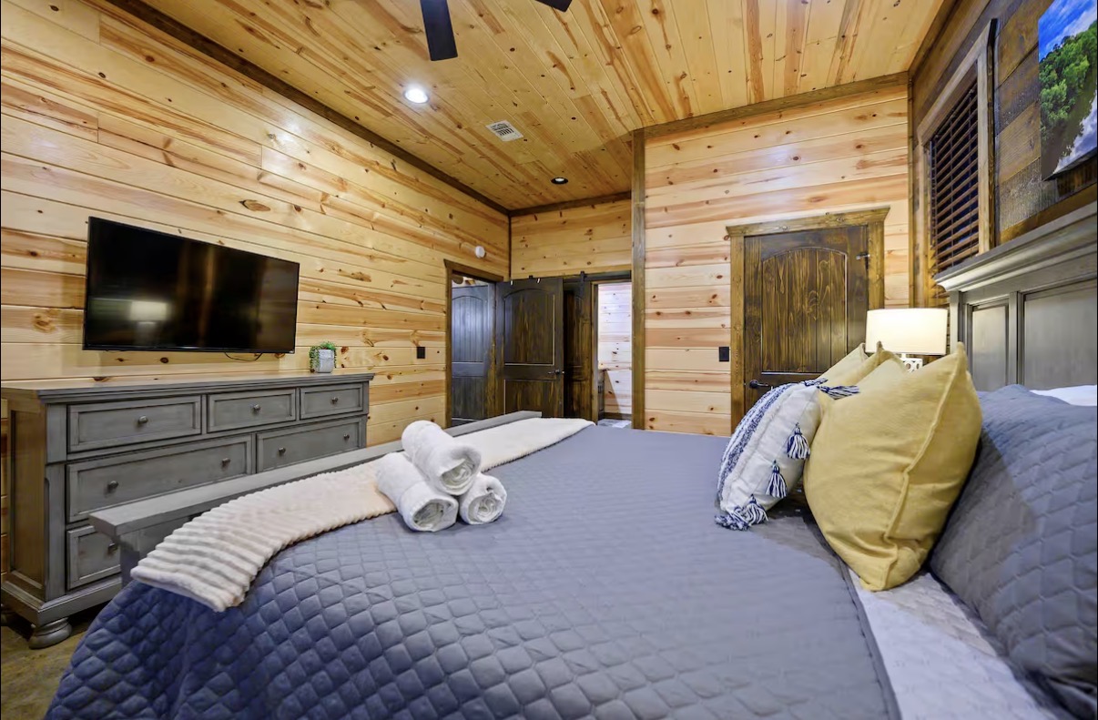 Sound of Sunshine — king bedroom with mounted TV, dresser and en-suite doorway