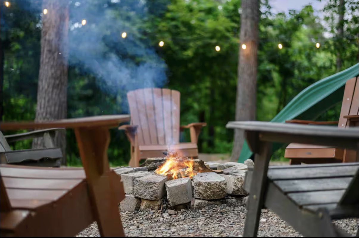 Sound of Sunshine — fire pit with Adirondack chairs and string lights in the pines