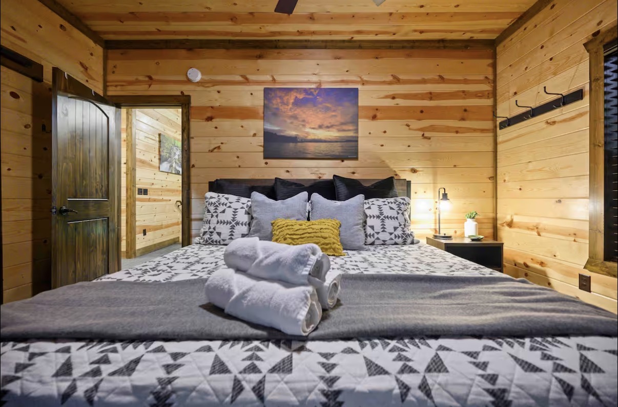 Sound of Sunshine — king bedroom head-on with sunset canvas and en-suite entry